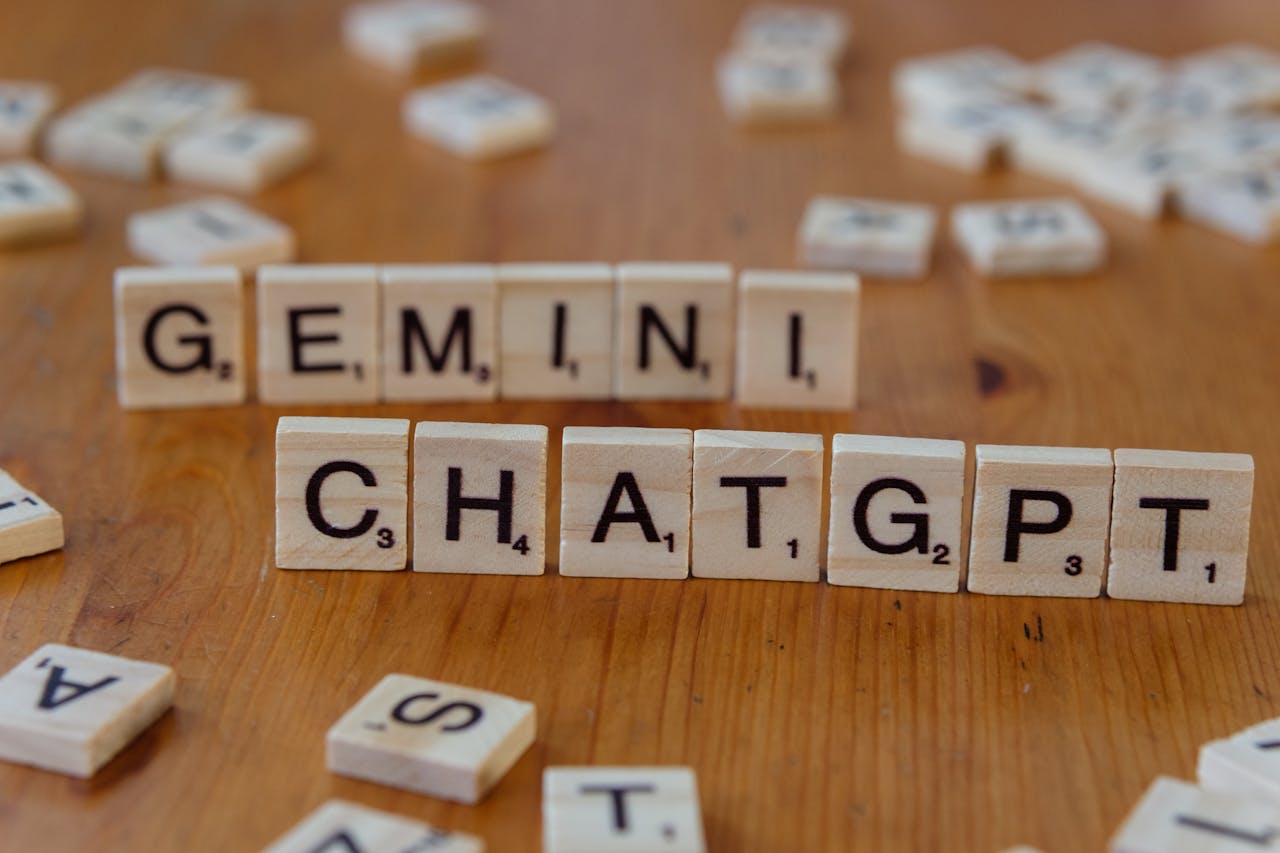 gallery-04 Close-up of wooden Scrabble tiles spelling Gemini and ChatGPT on a wooden surface.