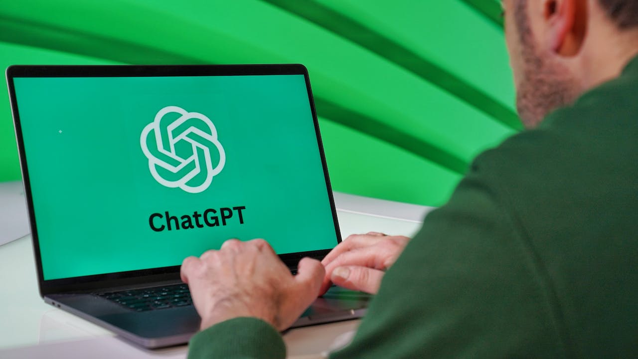 gallery-02 Person typing on a laptop displaying ChatGPT logo with a green vibrant setting.